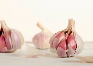 Three whole garlic bulbs with cloves with on a white surface