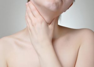 Woman with head tilted to one side holding her neck in pain