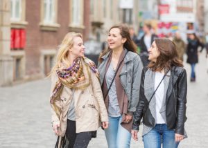 A group of three young women walking down a street and chatting with each other