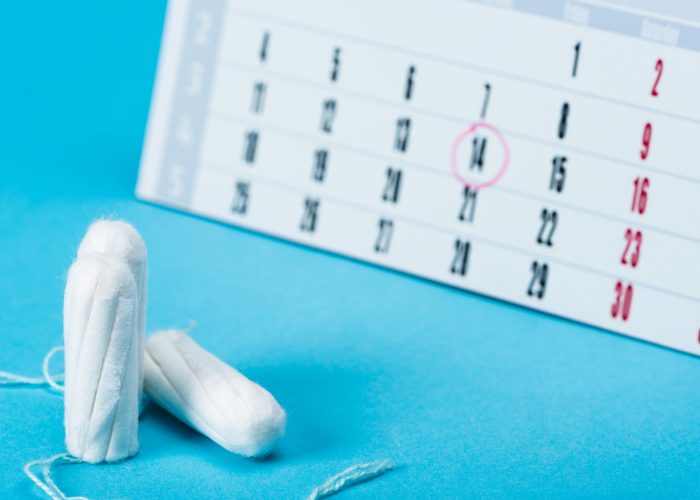 Tampons on a blue table in front of a calendar with a circle around the 14th in the background
