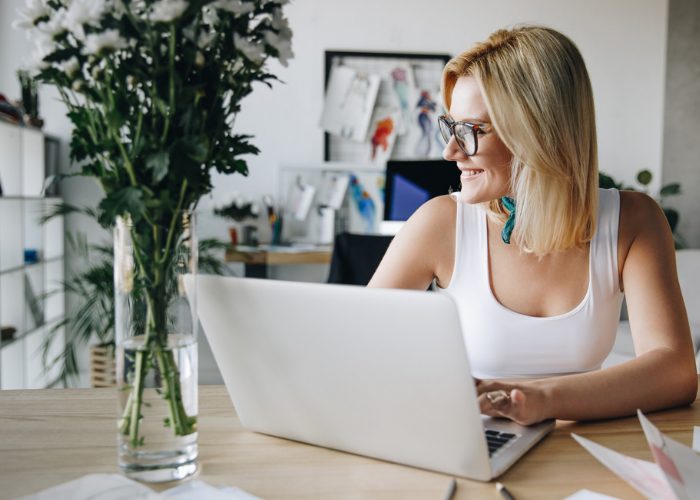 Woman smiling while typing on her laptop in her home office