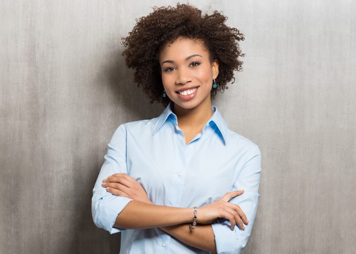 Confident African American woman smiling in a blue shirt with her arms crossed over in front
