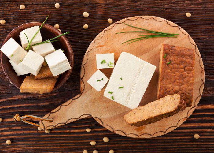 Tofu and tempeh rich in the amino acid threonine, laid out on a wooden board and wooden bowl on a wooden table