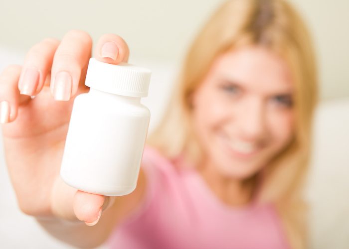 Woman holding an unlabelled bottle of B12 vitamins