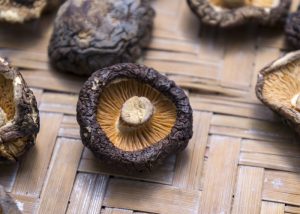 Dried black shiitake mushrooms on a woven wooden mat
