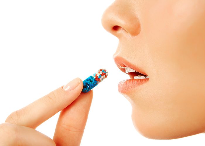 Closeup of woman putting a vitamin pill in her mouth