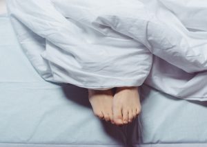 Woman's feet sticking out from under her weighted blanket in bed