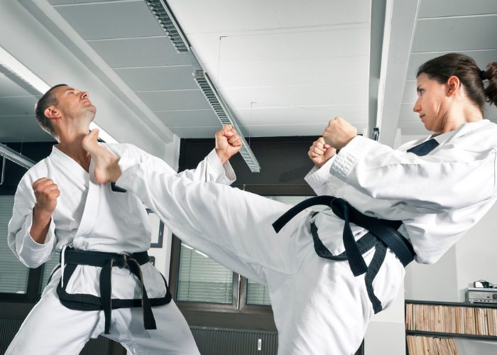 Matrial arts karate black belt woman high kicking her practice partner in the neck