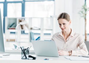 Woman working on her laptop at her desk in her office