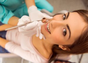 Woman with adult braces sat in a dentist's chair smiling