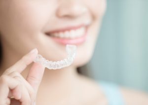 Woman holding onto invisible Invisalign braces and smiling