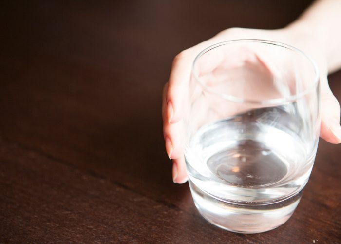Close up of a woman's hand holding onto a glass of water