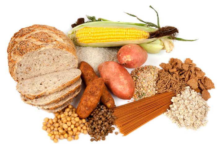 Different complex carb foods like corn, grains, tubers, beans, laid out on a white surface
