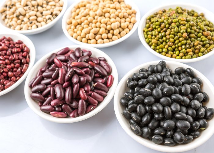 A variety of beans like black beans, green beans, red kidney beans, in white bowls