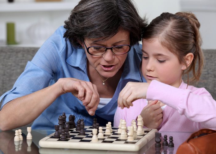 Mother teaching her daughter how to play chess for brain training