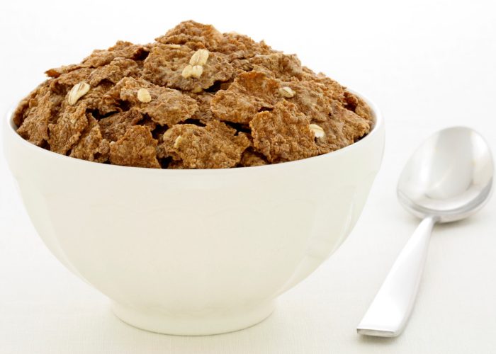 Bowl of wheat bran cereal in a white bowl and a spoon next to it