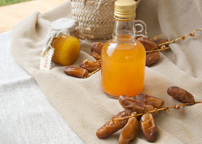 Bottle of date vinegar on a brown cloth with fresh dates around it