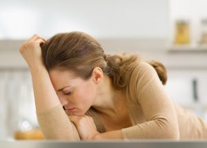 Depressed woman laying on the kitchen counter with her head in her hands