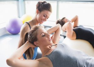 Female personal trainer coaching a ladies workout class involving exercise balls