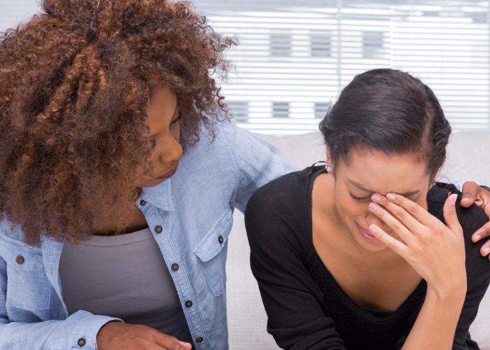 One woman comforting another crying woman