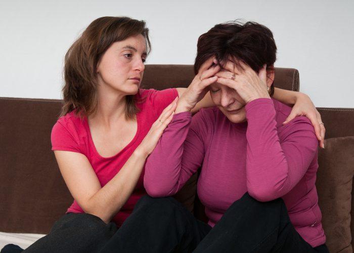 A tired-looking daughter caring for her depressed mother