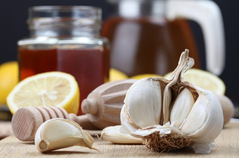 natural antibiotics such as honey, and cloves of garlic on a wooden table