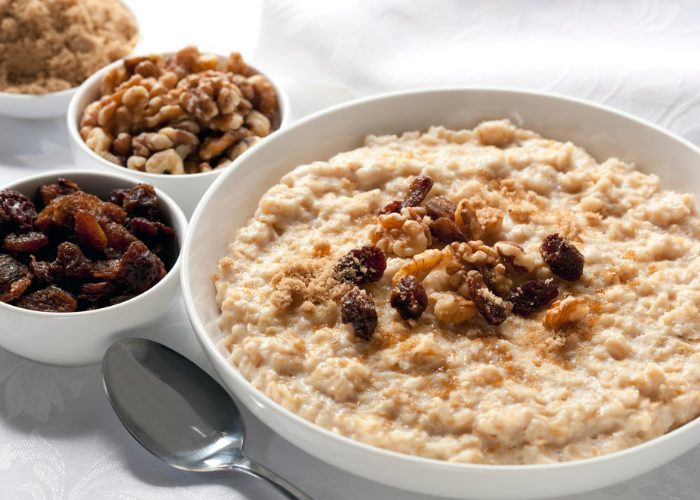 A bowl of freshly made Morning Honey Oats topped with raisins, walnuts, and brown sugar 