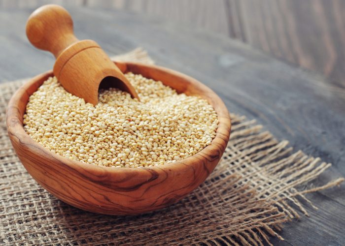 Wooden bowl with a scoop filled with quinoa 