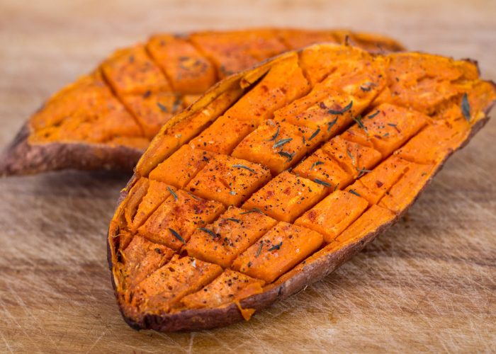 Two halves of a sweet baked potato laid on a wooden board