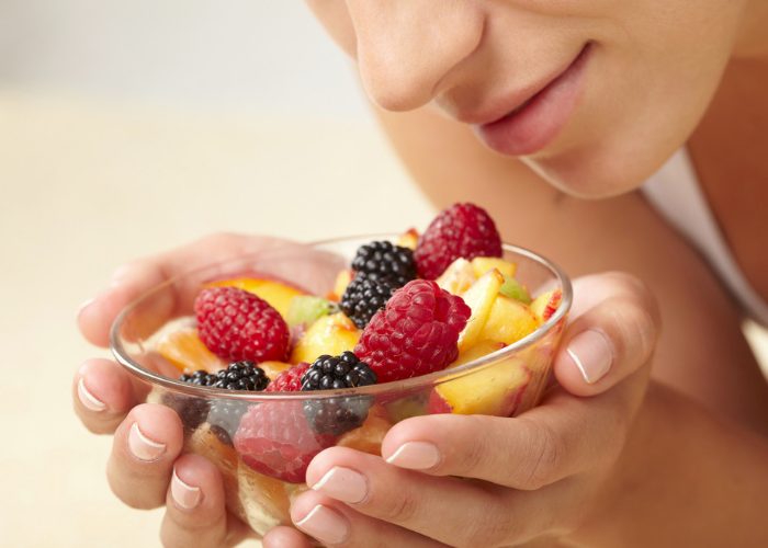 Woman holding a bowl of mixed cut fruits