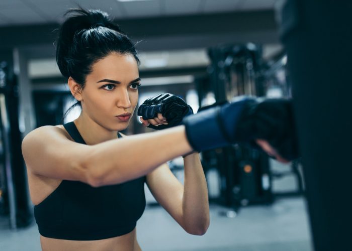 Woman in a gym practicing kickboxing punches on a punching bag