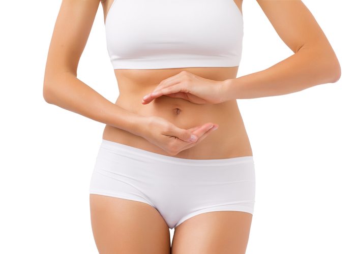 A woman in her underwear holding her stomach to represent a healthy digestive tract