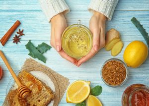 Top-down view of a woman holding a warm glass of lemon and ginger tea