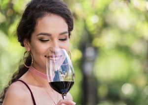 A woman smelling a glass of red wine at a party
