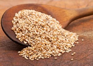 A wooden spoon filled with sesame seeds