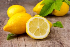 Whole lemons and a halved lemon on a wooden board