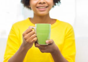 Woman holding up a cup of detox tea ready to drink it