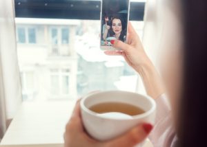 Woman taking a selfie of herself drinking a cup of detox tea
