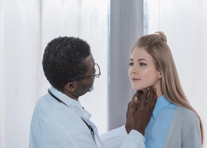 Doctor examining a patient's thyroids using his hands