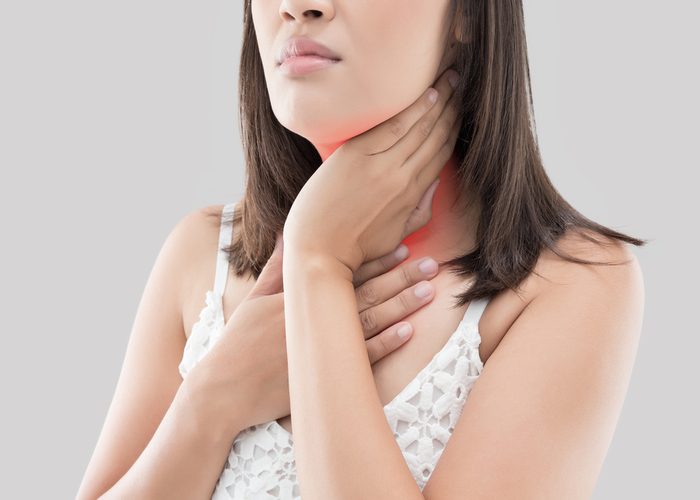 Woman holding her neck in pain due to thyroid disease