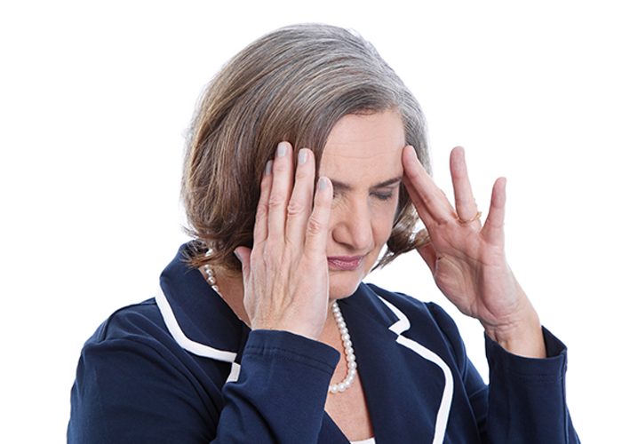 Elderly woman in blue suit jacket with headache touching her temples with both hands