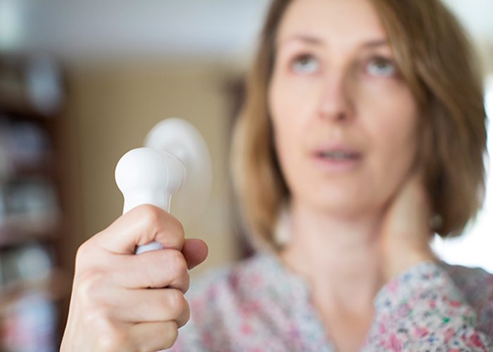 Menopausal woman holding electric fan to cool down