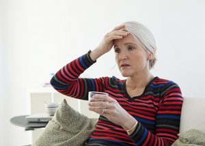 Elderly woman with white hair experiencing a headache, side effect from menopause