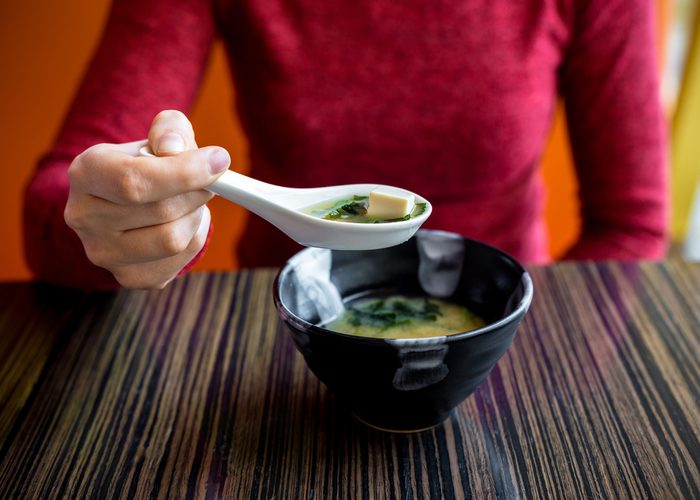 Woman eating a bowl of miso soup at a restaurant