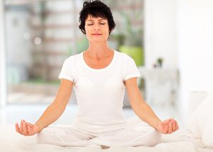 Middle aged woman dressed in white meditating