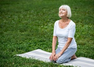 Elderly lady meditating in a park