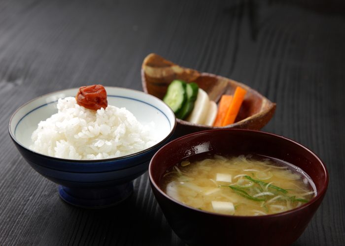 Typical Japanese sides including a bowl of miso soup, a rice topped with an umeboshi, and pickled vegetables