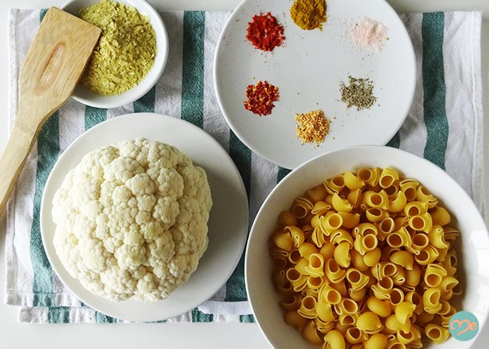 Top down view of dairy-free mac and cheese ingredients such as cauliflower, macaroni, and various spices