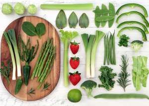 Top-down shot of various fresh vegetables presented neatly on a white table