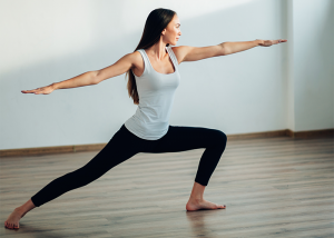 Woman holding warrior pose during hot yoga
